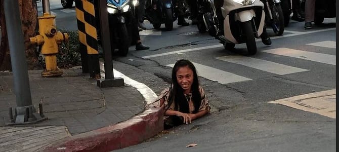 Una donna senzatetto a Manila uscita da uno scolo